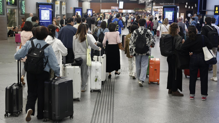 Varias personas esperan la salida de su tren en la estación de Atocha en Madrid este domingo