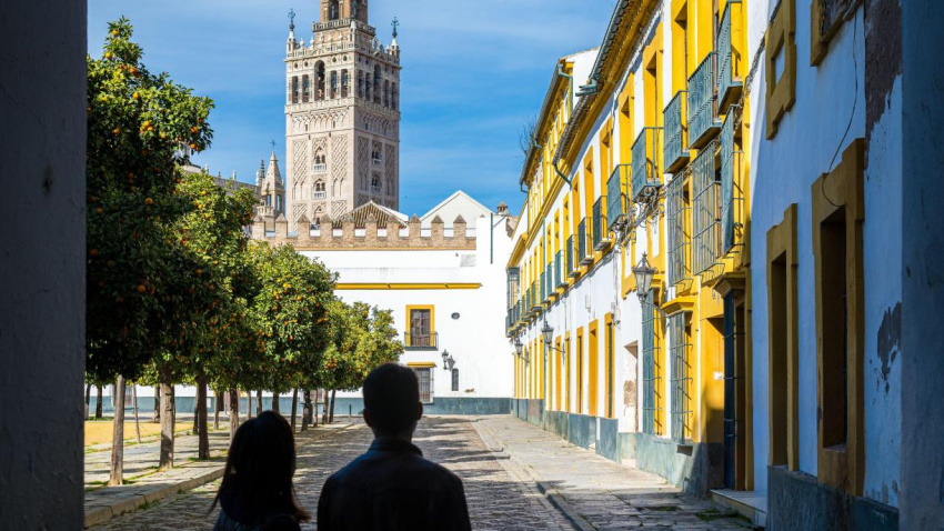 Pareja joven admirando la torre de la Giralda desde la plaza del Patio de Banderas, Sevilla, España