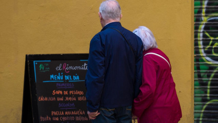 Una pareja mayor lee el menú de un restaurante mientras se toman de la mano