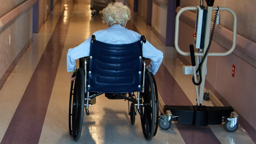 Una mujer pasea en silla de ruedas por el pasillo de una residencia de ancianos