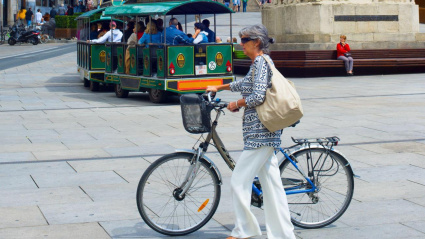Mujer elegante mayor con bicicleta en la plaza central de España de Vitoria-Gasteiz, España