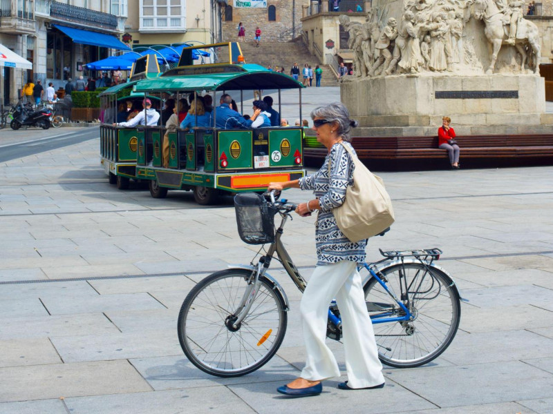 Mujer elegante mayor con bicicleta en la plaza central de España de Vitoria-Gasteiz, España