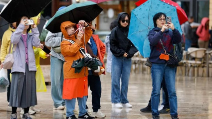 Un grupo de turistas asiáticos disfrutan del puente a pesar del tiempo