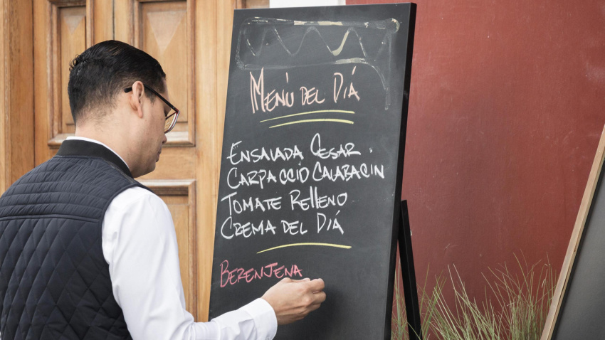 Un camarero apunta el menú del día de un restaurante en una pizarra