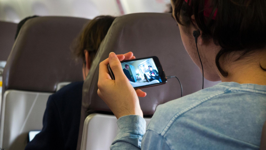 Un joven utiliza su teléfono móvil en pleno vuelo
