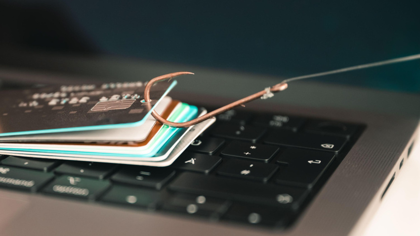 Un anzuelo recoge varias tarjetas de crédito frente a un ordenador portátil