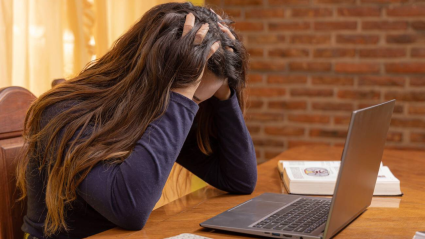 Una chica joven estresada delante de su ordenador de trabajo sin poder concentrarse