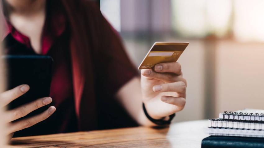 Una mujer utiliza su tarjeta de crédito para pagar una compra online con su móvil