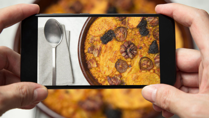 Un hombre toma una foto de un plato de arroz al horno en Valencia