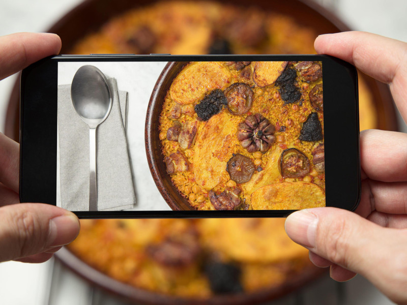 Un hombre toma una foto de un plato de arroz al horno en Valencia