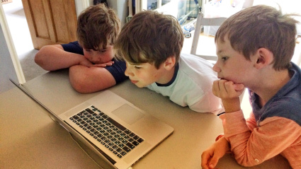 Tres niños comparten un ordenador para jugar