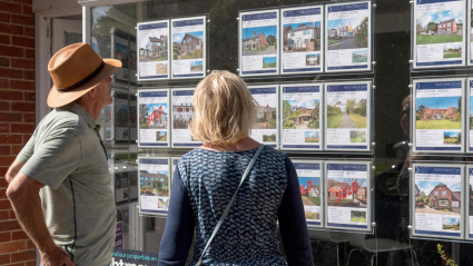 Una pareja mira en el escaparate de una inmobiliaria los anuncios de pisos