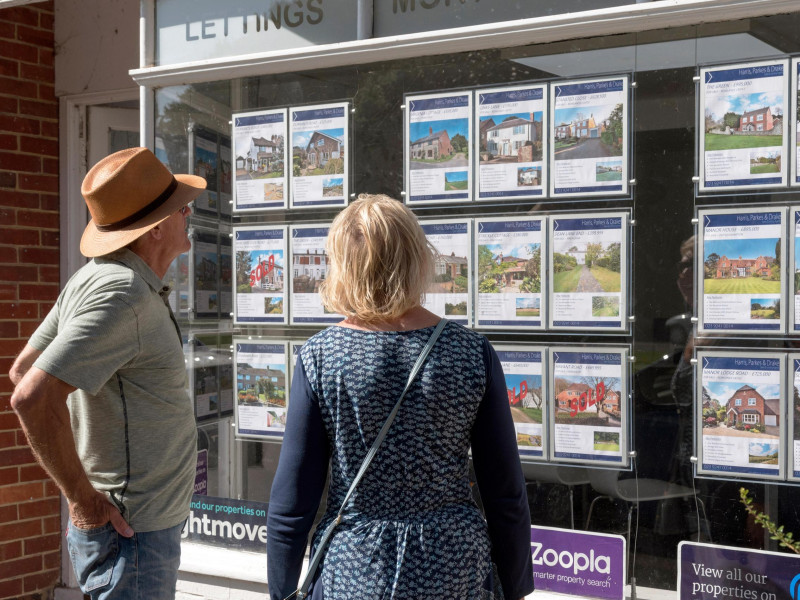 Una pareja mira en el escaparate de una inmobiliaria los anuncios de pisos