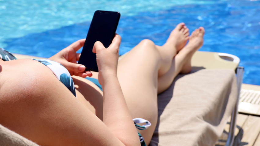 Una mujer utiliza su teléfono móvil durante un caluroso día de piscina