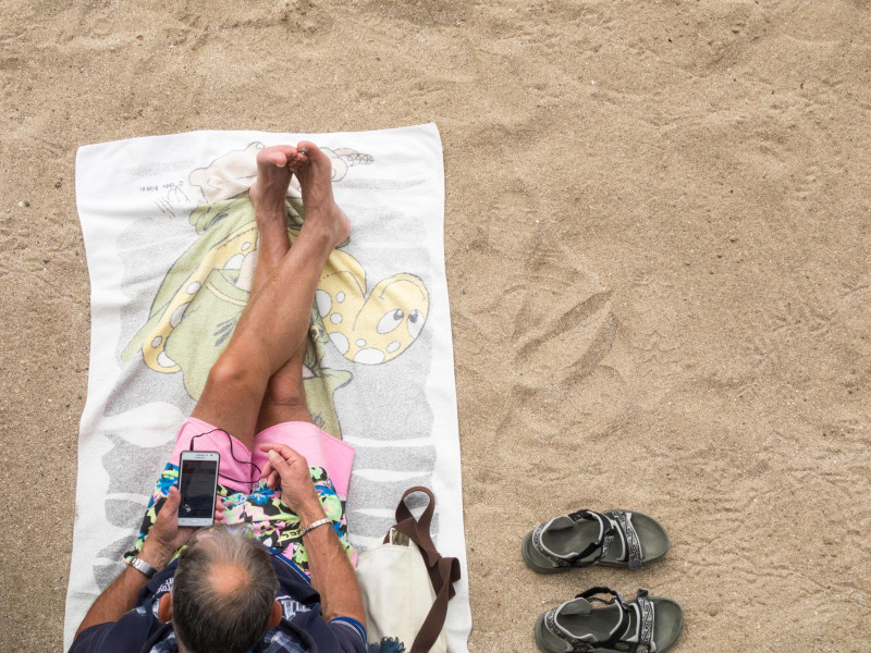 Un hombre mayor utiliza su teléfono móvil en la playa