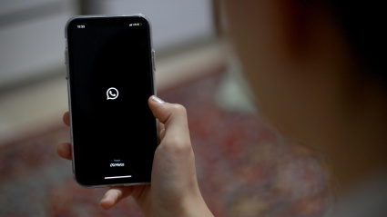 Una mujer mira el icono de WhatsApp en la pantalla de su móvil tras bloquear la aplicación