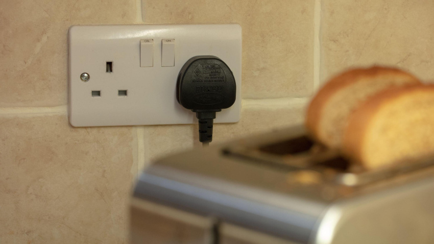 Una tostadora enchufada a la corriente con dos rebanadas de pan