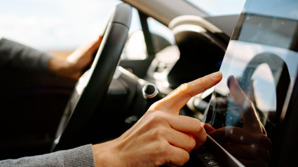 Un conductor toca la pantalla táctil de un moderno navegador GPS