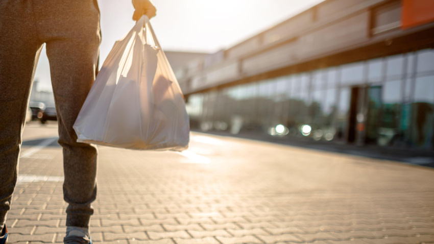 Un hombre sostiene una bolsa de plástico en un parking situado a pie de calle
