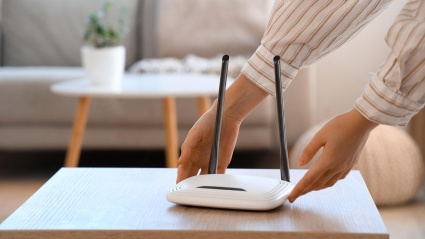 Una mujer coge un router wifi para moverlo y conseguir una mejor conexión