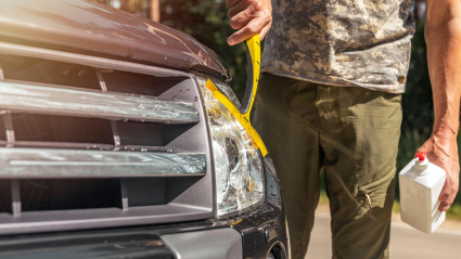 Un hombre limpia y enjabona los faros de su coche