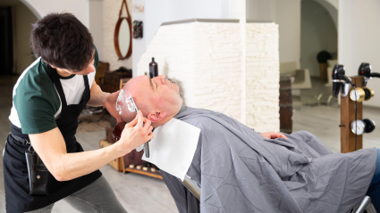 Un barbero afeitando la cabeza de un cliente