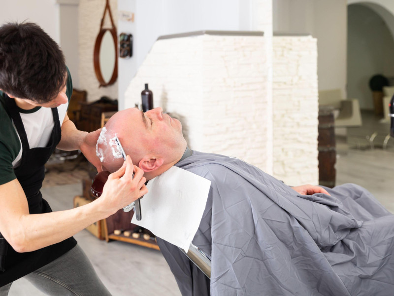 Un barbero afeitando la cabeza de un cliente