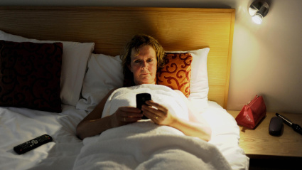 Una mujer utiliza su teléfono móvil en la cama antes de irse a dormir