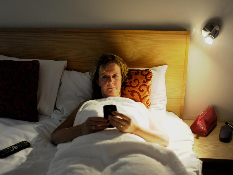 Una mujer utiliza su teléfono móvil en la cama antes de irse a dormir