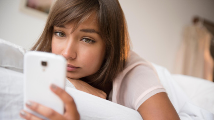 Una joven utilizando su teléfono móvil aburrida