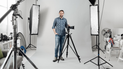 Un fotógrafo profesional enseña su estudio mientras sostiene una cámara digital