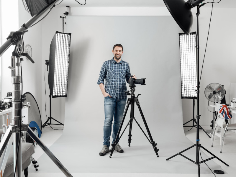 Un fotógrafo profesional enseña su estudio mientras sostiene una cámara digital