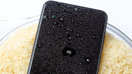 Un teléfono móvil mojado secándose en un bol con arroz