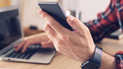 Un hombre utiliza un smartphone y un ordenador portátil en su casa