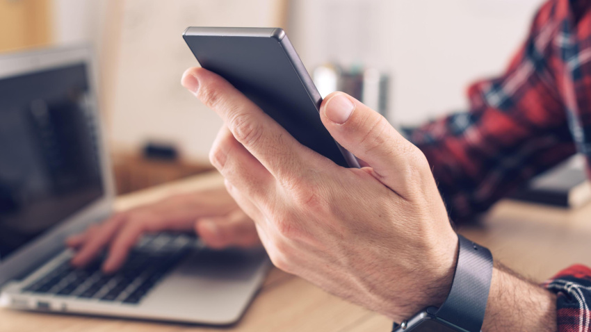 Un hombre utiliza un smartphone y un ordenador portátil en su casa