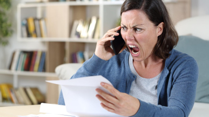 Una mujer adulta cabreada mientras recibe una llamada telefónica