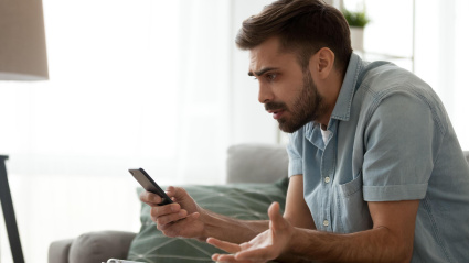 Un hombre confuso mientras mira mensajes de spam