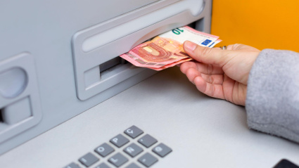 Una persona retira dinero en efectivo de un cajero automático