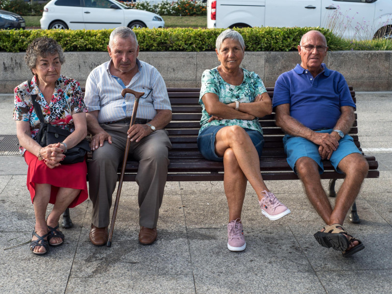 Varias personas mayores sentadas en un banco pasando la tarde en Santander