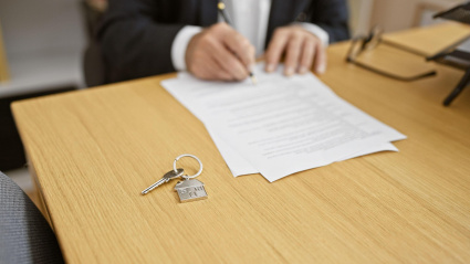 2TA210W Hardworking senior man real state agent signing off success in office, hands busily writing contract on elegant desk