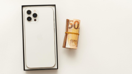 iPhone 12 pro max junto a un taco de billetes enrollados