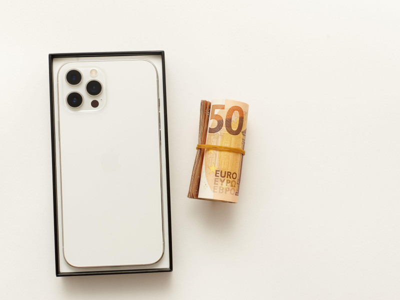 iPhone 12 pro max junto a un taco de billetes enrollados