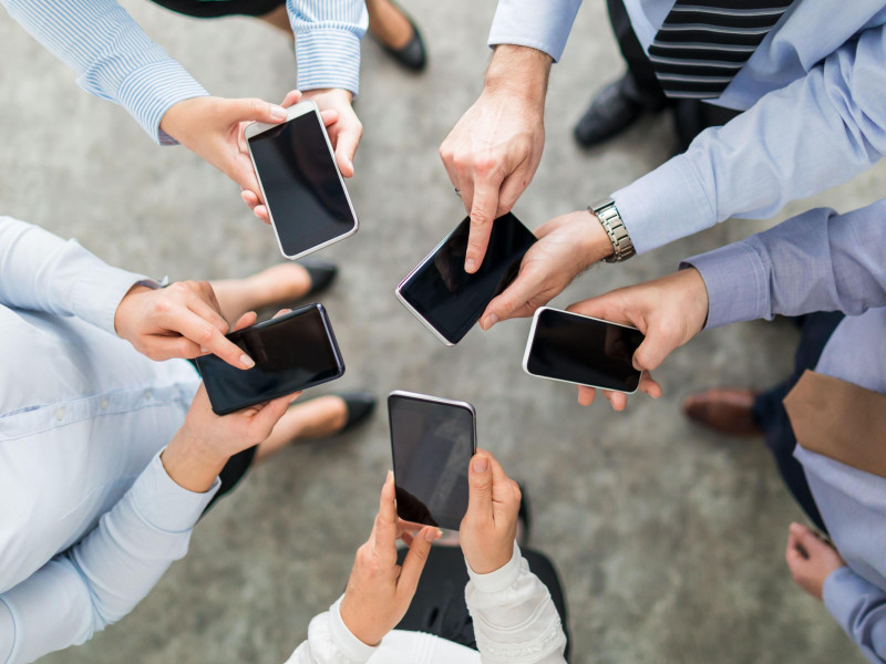 Un grupo de amigos sujetando sus teléfonos móviles