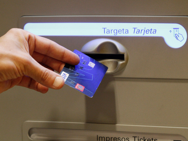 Una persona introduce una tarjeta de crédito en un cajero
