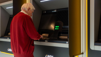 Un hombre mayor sacando dinero del cajero