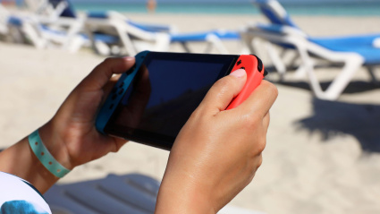 Una mujer jugando a la Nintendo Switch en la playa