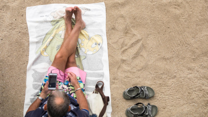 Un hombre utilizando su móvil en la playa