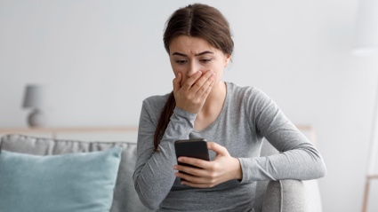Una mujer en shock con su teléfono móvil