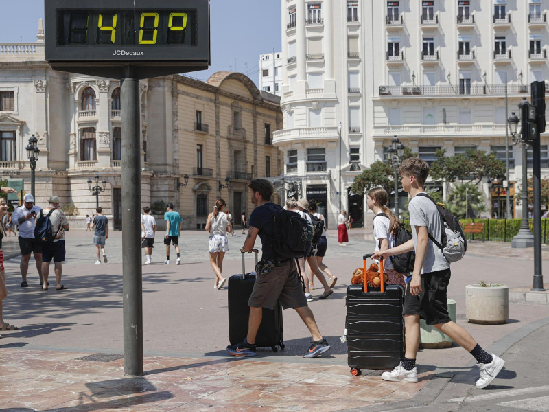 Varios turistas acarrean sus maletas este viernes 15 de agosto por la plaza del Ayuntamiento de València