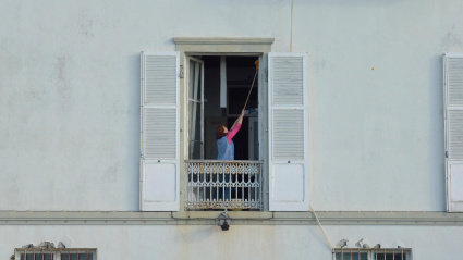 Una empleada del hogar limpiando las ventanas